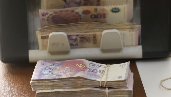 Argentine pesos from a client buying U.S. dollars are counted by a machine at an illegal exchange location in Buenos Aires, Argentina, Thursday, Dec. 17, 2015 - Sputnik International