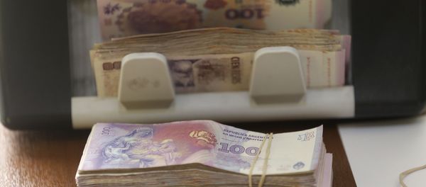Argentine pesos from a client buying U.S. dollars are counted by a machine at an illegal exchange location in Buenos Aires, Argentina, Thursday, Dec. 17, 2015 - Sputnik International