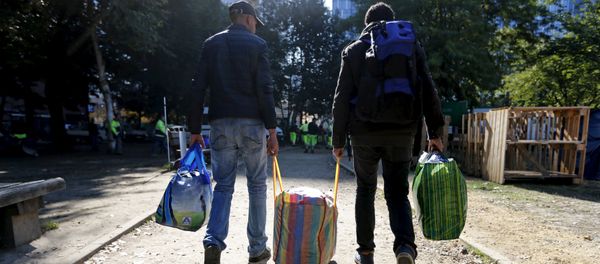 Migrants carry their belongings as they leave a makeshift camp for refugees outside the foreign office in Brussels, Belgium October 2, 2015 - Sputnik International