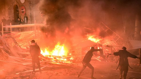Protestors throw projectiles in a burning barricade during a demonstration of yellow vests (gilets jaunes) against rising costs of living they blame on high taxes in Toulouse, southern France, on December 8, 2018 Protestors throw projectiles in a burning barricade during a demonstration of yellow vests (gilets jaunes) against rising costs of living they blame on high taxes in Toulouse, southern France, on December 8, 2018 - Sputnik International