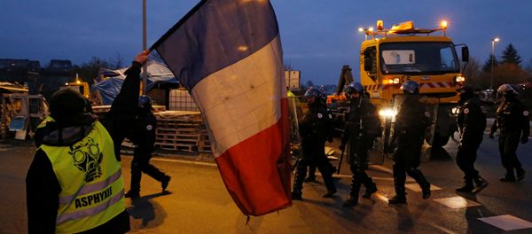 A protester wearing a yellow vests holds a French flag as police arrive to secure the site as their shelter at a traffic island is dismantled near the A2 Paris-Brussels motorway in Fontaine-Notre-Dame, France, December 14, 2018 - Sputnik International