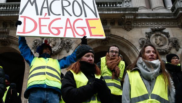 French activist Jean-Baptiste Redde, aka Voltuan, wearing a yellow vest (gilet jaune) holds a cardboard reading Macron go away during a demonstration in front of the Opera House in Paris against rising costs of living blamed on high taxes, on December 15, 2018 French activist Jean-Baptiste Redde, aka Voltuan, wearing a yellow vest (gilet jaune) holds a cardboard reading Macron go away during a demonstration in front of the Opera House in Paris against rising costs of living blamed on high taxes, on December 15, 2018 - Sputnik International