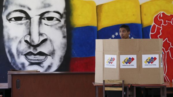 A voter chooses his candidate next to a mural of late Venezuelan President Hugo Chavez during presidential elections in Caracas, Venezuela - Sputnik International