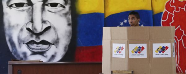 A voter chooses his candidate next to a mural of late Venezuelan President Hugo Chavez during presidential elections in Caracas, Venezuela A voter chooses his candidate next to a mural of late Venezuelan President Hugo Chavez during presidential elections in Caracas, Venezuela - Sputnik International