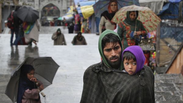 A Kashmiri man covers his son under his robe, locally known as phiran, from cold weather in Srinagar, Indian controlled Kashmir, Thursday, March 17, 2016 - Sputnik International