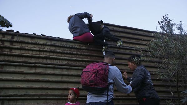 Honduran migrants help each other to cross over the U.S. border wall to San Diego, California, from Tijuana, Mexico, Saturday, Dec. 15, 2018 - Sputnik International