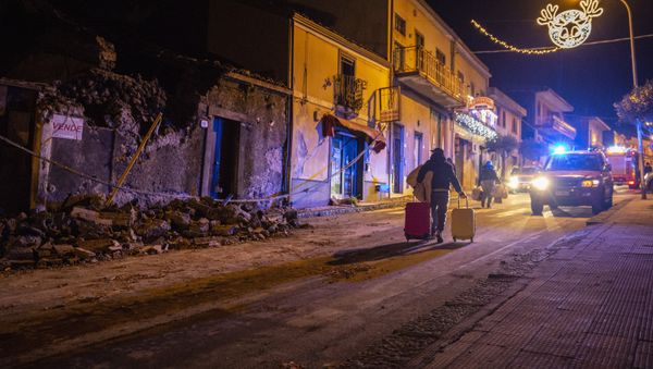A man carries his belongings as he walks past debris of a partially collapsed house in Fleri, Sicily Italy, Wednesday, Dec. 26, 2018 A man carries his belongings as he walks past debris of a partially collapsed house in Fleri, Sicily Italy, Wednesday, Dec. 26, 2018 - Sputnik International