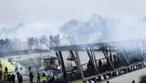 Tear gas is thrown by riot police as demonstrators wearing yellow vests try to cross a pedestrian bridge during march in Paris, Saturday, Jan. 5, 2019. Tear gas is thrown by riot police as demonstrators wearing yellow vests try to cross a pedestrian bridge during march in Paris, Saturday, Jan. 5, 2019. - Sputnik International
