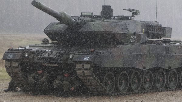 Polish troops take shelter from pouring rain under the belly of a tank during a ceremony welcoming a deployment of new NATO troops in Orzysz, northeast Poland - Sputnik International