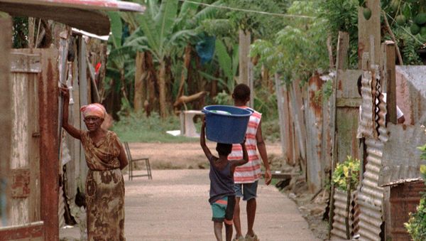 A boy carries a bucket on his head in a small village located in the shadows of banana plantations in the Roseau vally southeast of Castries, St. Lucia - Sputnik International