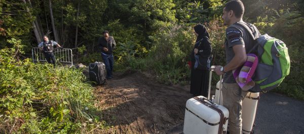 RCMP officers speaks with migrants as they prepare to cross the US/Canada border illegally near Hemmingford, Quebec, August 20, 2017 RCMP officers speaks with migrants as they prepare to cross the US/Canada border illegally near Hemmingford, Quebec, August 20, 2017 - Sputnik International