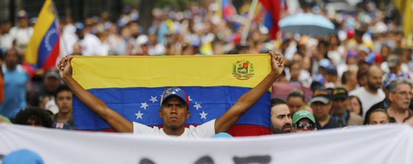 An opposition member holds a Venezuelan national flag during a protest march against President Nicolas Maduro in Caracas, Venezuela, Wednesday, Jan. 23, 2019. An opposition member holds a Venezuelan national flag during a protest march against President Nicolas Maduro in Caracas, Venezuela, Wednesday, Jan. 23, 2019. - Sputnik International