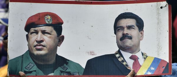 A supporter of President Nicolas Maduro's government holds a banner with the portraits of late Venezuelan president Hugo Chavez (L) and President Nicolas Maduro, while taking part in a march, on the anniversary of 1958 uprising that overthrew military dictatorship in Caracas on January 23, 2019. A supporter of President Nicolas Maduro's government holds a banner with the portraits of late Venezuelan president Hugo Chavez (L) and President Nicolas Maduro, while taking part in a march, on the anniversary of 1958 uprising that overthrew military dictatorship in Caracas on January 23, 2019. - Sputnik International