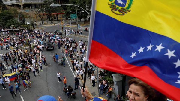 A supporter of Venezuelan opposition leader and self-proclaimed interim president Juan Guaido holds a flag while taking part in a protest against Venezuelan President Nicolas Maduro's government in Caracas, Venezuela January 30, 2019. A supporter of Venezuelan opposition leader and self-proclaimed interim president Juan Guaido holds a flag while taking part in a protest against Venezuelan President Nicolas Maduro's government in Caracas, Venezuela January 30, 2019. - Sputnik International