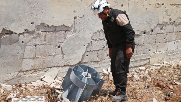 A member of the Syrian civil defence volunteers, also known as the White Helmets, stands next to the tail fin of a bomb as local bomb-disposal experts search for unexploded ordnance in a rebel-held area of Daraa on July 20, 2017 - Sputnik International
