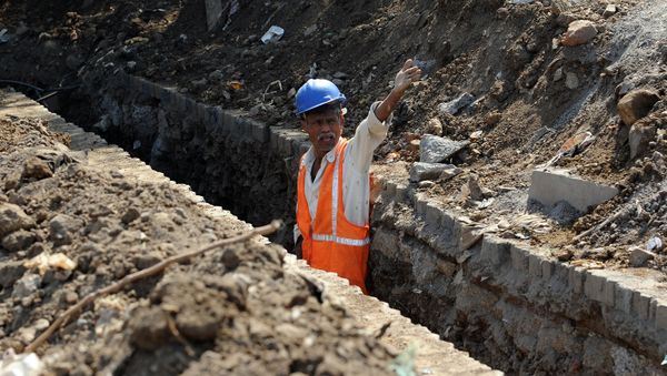 A labourer shouts instructions to co-workers standing inside a trench dug by the side of a busy throughfare to lay power cables in Mumbai on January 7, 2012 - Sputnik International