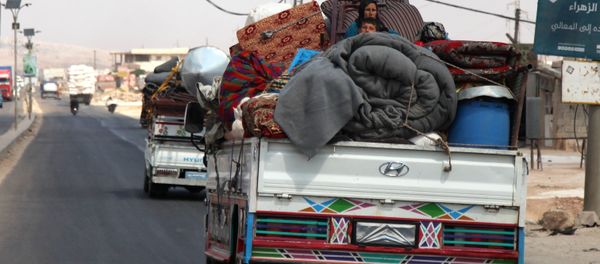 Syrians ride with their belongings in trucks as they head to safer areas in the town of Khan Sheikhun. - Sputnik International