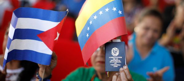 A supporter of Venezuela's President Nicolas Maduro holding a copy of the Venezuelan constitution and flags of Venezuela and Cuba, takes part in a gathering in support of his government outside the Miraflores Palace in Caracas, Venezuela January 26, 2019 A supporter of Venezuela's President Nicolas Maduro holding a copy of the Venezuelan constitution and flags of Venezuela and Cuba, takes part in a gathering in support of his government outside the Miraflores Palace in Caracas, Venezuela January 26, 2019 - Sputnik International