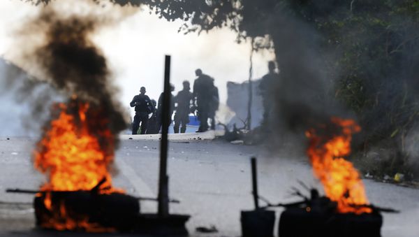 Bolivarian National Police stand behind a burning roadblock set up by anti-government protesters who are showing support for a mutiny by some National Guard soldiers in the Cotiza neighborhood of Caracas, Venezuela, Monday, Jan. 21, 2019 - Sputnik International