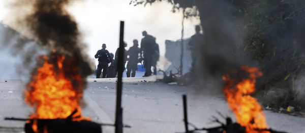 Bolivarian National Police stand behind a burning roadblock set up by anti-government protesters who are showing support for a mutiny by some National Guard soldiers in the Cotiza neighborhood of Caracas, Venezuela, Monday, Jan. 21, 2019 Bolivarian National Police stand behind a burning roadblock set up by anti-government protesters who are showing support for a mutiny by some National Guard soldiers in the Cotiza neighborhood of Caracas, Venezuela, Monday, Jan. 21, 2019 - Sputnik International