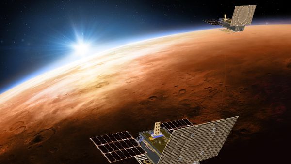 This illustration made available by NASA on March 29, 2018 shows the twin Mars Cube One (MarCO) spacecraft flying over Mars with Earth and the sun in the distance - Sputnik International