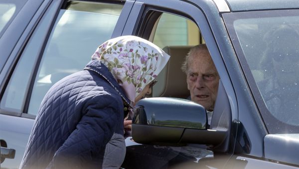 Britain's Prince Philip sits in the driving seat of a car, talking to his wife, Queen Elizabeth II - Sputnik International