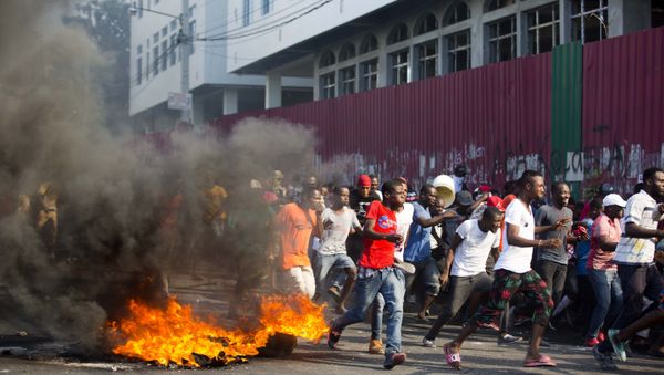 Demonstrators run away during a protest to demand the resignation of President Jovenel Moise and demanding to know how Petro Caribe funds have been used by the current and past administrations, in Port-au-Prince, Haiti, Saturday, Feb. 9, 2019. Much of the financial support to help Haiti rebuild after the 2010 earthquake comes from Venezuela's Petro Caribe fund, a 2005 pact that gives suppliers below-market financing for oil and is under the control of the central government. - Sputnik International