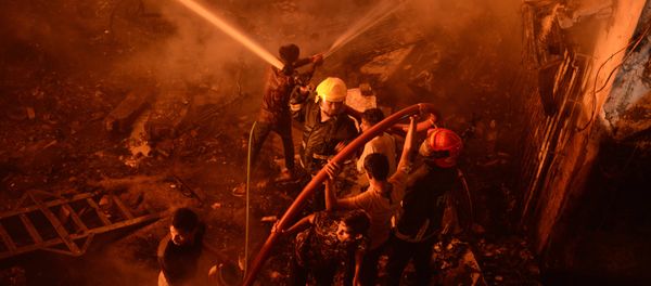 In this Wednesday, Feb. 20, 2019, photo, firefighters try to douse flames in Dhaka, Bangladesh. - Sputnik International