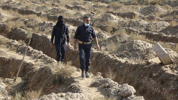 This frame grab from a video provided on Thursday, Nov. 22, 2018, shows Syrian workers of a Raqqa group walk at the site of a mass grave believed to contain the bodies of civilians and Islamic State militants, in Raqqa. A local official in the city of Raqqa says more than 500 bodies have so far been exhumed from one of the largest mass graves discovered in the city. The northern Syrian city was once the de facto capital of the Islamic State group and was liberated in a campaign that ended more than a year ago, but rescuers and early recovery teams continue to locate mass graves scattered around the city. - Sputnik International