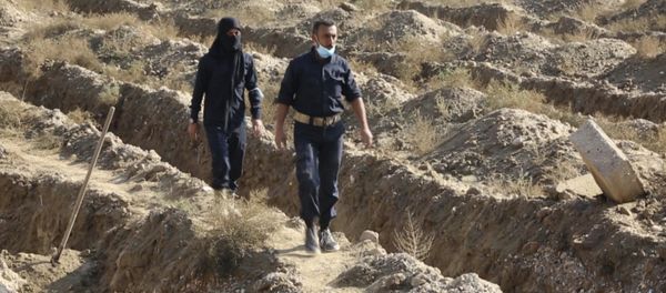 This frame grab from a video provided on Thursday, Nov. 22, 2018, shows Syrian workers of a Raqqa group walk at the site of a mass grave believed to contain the bodies of civilians and Islamic State militants, in Raqqa. A local official in the city of Raqqa says more than 500 bodies have so far been exhumed from one of the largest mass graves discovered in the city. The northern Syrian city was once the de facto capital of the Islamic State group and was liberated in a campaign that ended more than a year ago, but rescuers and early recovery teams continue to locate mass graves scattered around the city. This frame grab from a video provided on Thursday, Nov. 22, 2018, shows Syrian workers of a Raqqa group walk at the site of a mass grave believed to contain the bodies of civilians and Islamic State militants, in Raqqa. A local official in the city of Raqqa says more than 500 bodies have so far been exhumed from one of the largest mass graves discovered in the city. The northern Syrian city was once the de facto capital of the Islamic State group and was liberated in a campaign that ended more than a year ago, but rescuers and early recovery teams continue to locate mass graves scattered around the city. - Sputnik International