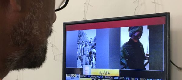 A man looks at a television screen displaying the pictures of the Indian pilots, said to be captured by Pakistan after shooting down two Indian planes, in Karachi, Pakistan February 27, 2019 - Sputnik International