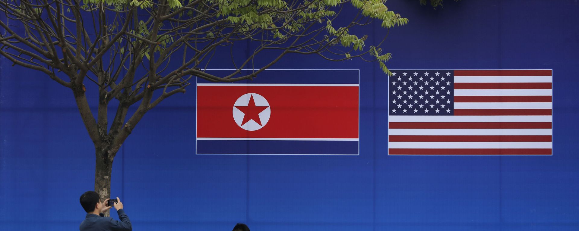 People take pictures in front of a poster featuring the upcoming second summit between the U.S. and North Korea in Hanoi, Vietnam - Sputnik International, 1920, 29.03.2021
