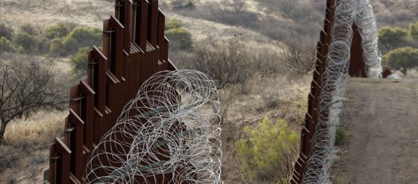 A razor-wire-covered border wall separates the United States, at left, from Mexico east of Nogales, Ariz - Sputnik International