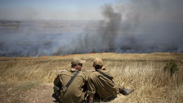 Israeli soldiers sit in a position on the Israeli-controlled Golan Heights as smoke rises following explosions of mortar shells (File) Israeli soldiers sit in a position on the Israeli-controlled Golan Heights as smoke rises following explosions of mortar shells (File) - Sputnik International