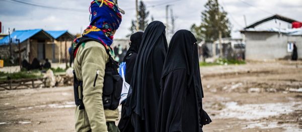Foreign women, living in al-Hol camp which houses relatives of Islamic State (IS) group members, walk under the supervision of a fighter of the Syrian Democratic Forces (SDF) in the camp in al-Hasakeh governorate in northeastern Syria on March 28, 2019 Foreign women, living in al-Hol camp which houses relatives of Islamic State (IS) group members, walk under the supervision of a fighter of the Syrian Democratic Forces (SDF) in the camp in al-Hasakeh governorate in northeastern Syria on March 28, 2019 - Sputnik International