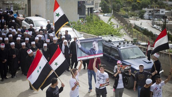 Druze men carry Syrian flags and pictures of Syrian President Bashar Assad during a rally marking Syria's Independence Day, in the Druze village of Ein Qiniyye, Israeli-controlled Golan Heights, Tuesday, April 17, 2018. Druze men carry Syrian flags and pictures of Syrian President Bashar Assad during a rally marking Syria's Independence Day, in the Druze village of Ein Qiniyye, Israeli-controlled Golan Heights, Tuesday, April 17, 2018. - Sputnik International