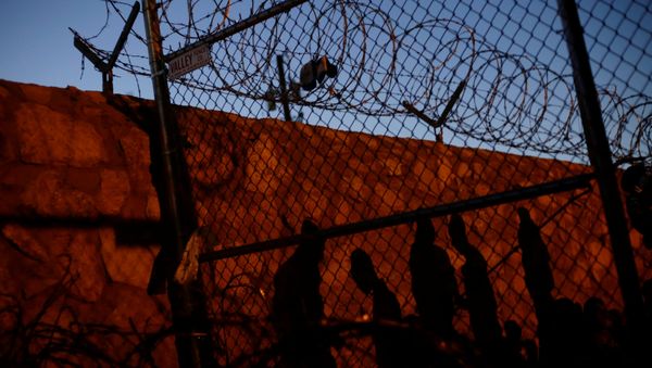 Central American migrants cast their shadows against a wall while inside an enclosure where they are being held after turning themselves in to request asylum, in El Paso - Sputnik International