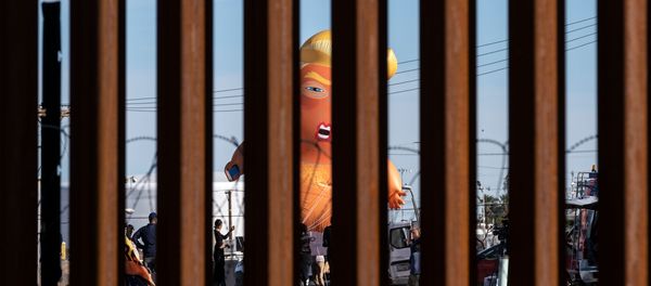 A satirical balloon of a baby US President Donald Trump is seen through the US-Mexico border fence during a demonstration against him prior to his visit to Calexico, California, as seen from Mexicali, Baja California state, Mexico, on April 5, 2019. - Sputnik International