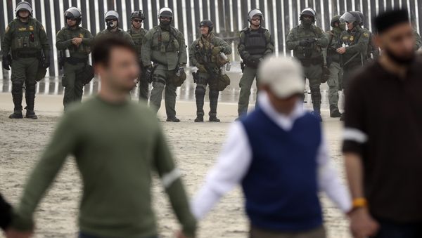 Border Patrol agents look on as a people hold hands and pray during a protest Monday, Dec. 10, 2018, in San Diego - Sputnik International
