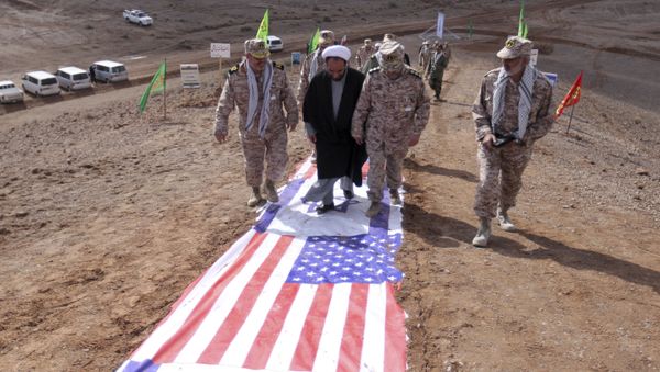 Members of Iran's Revolutionary Guard and a clergyman walk on the representations of the U.S. and Israeli flags Members of Iran's Revolutionary Guard and a clergyman walk on the representations of the U.S. and Israeli flags - Sputnik International
