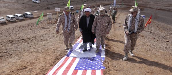 Members of Iran's Revolutionary Guard and a clergyman walk on the representations of the U.S. and Israeli flags Members of Iran's Revolutionary Guard and a clergyman walk on the representations of the U.S. and Israeli flags - Sputnik International