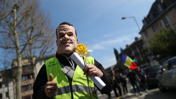 A demonstrator sporting a mask representing French President Emmanuel Macron holds a yellow flower during yellow vest protests, in Rouen on April 6, 2019 - Sputnik International