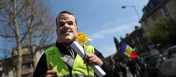 A demonstrator sporting a mask representing French President Emmanuel Macron holds a yellow flower during yellow vest protests, in Rouen on April 6, 2019 A demonstrator sporting a mask representing French President Emmanuel Macron holds a yellow flower during yellow vest protests, in Rouen on April 6, 2019 - Sputnik International