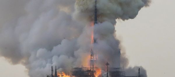 Flames and smoke are seen billowing from the roof at Notre-Dame Cathedral in Paris on April 15, 2019. A fire broke out at the landmark Notre-Dame Cathedral in central Paris, potentially involving renovation works being carried out at the site, the fire service said. - Sputnik International