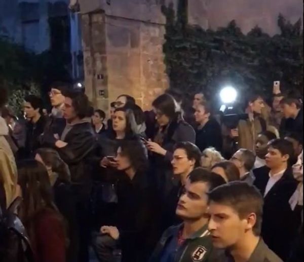 Parisians singing near burning Notre Dame Cathedral in Paris. - Sputnik International