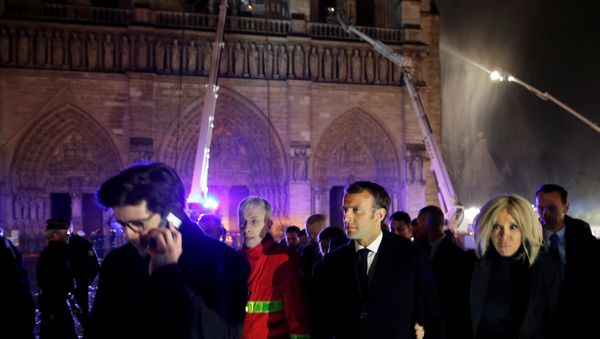 French President Emmanuel Macron and his wife Brigitte walk outside the Notre Dame Cathedral where a fire continues to burn in Paris on April 16, 2019. - Sputnik International