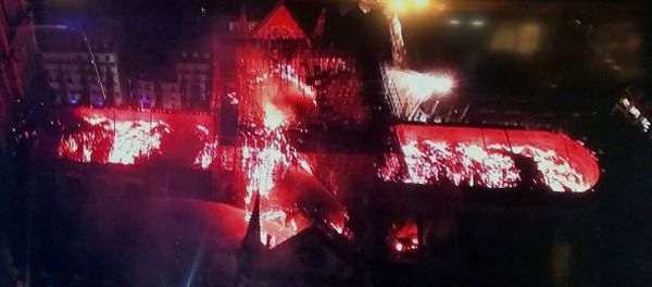 An image taken from a television screen shows an aerial view of the Notre Dame Cathedral engulfed in flames on 15 April, 2019, in the French capital Paris - Sputnik International