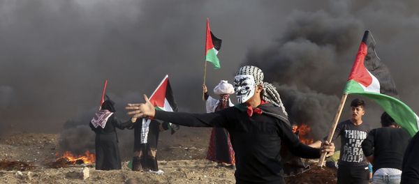 Protesters wave their national flags while others burn tires near the fence of Gaza Strip border with Israel during a protest east of Gaza City, Friday, Nov. 9, 2018 - Sputnik International