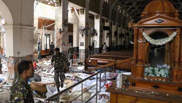 Sri Lankan security personnel walk past dead bodies covered with blankets amid blast debris at St. Anthony's Shrine following an explosion in the church in Kochchikade in Colombo on April 21, 2019. - Sputnik International