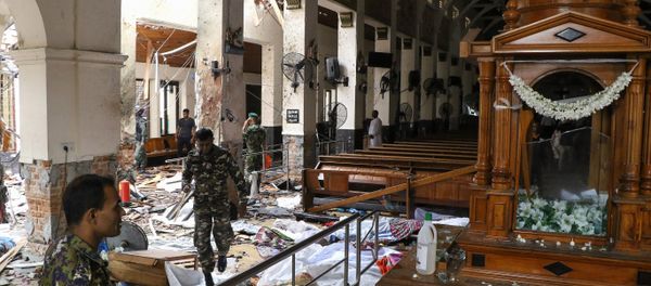 Sri Lankan security personnel walk past dead bodies covered with blankets amid blast debris at St. Anthony's Shrine following an explosion in the church in Kochchikade in Colombo on April 21, 2019. Sri Lankan security personnel walk past dead bodies covered with blankets amid blast debris at St. Anthony's Shrine following an explosion in the church in Kochchikade in Colombo on April 21, 2019. - Sputnik International